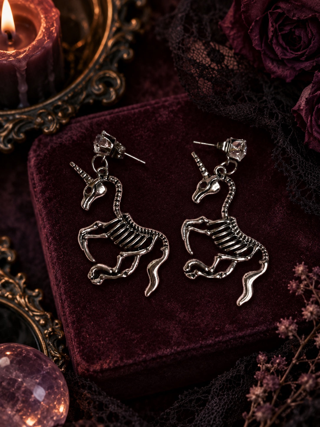 Silver-tone skeletal unicorn dangle earrings with clear faceted stud tops and push-back closures