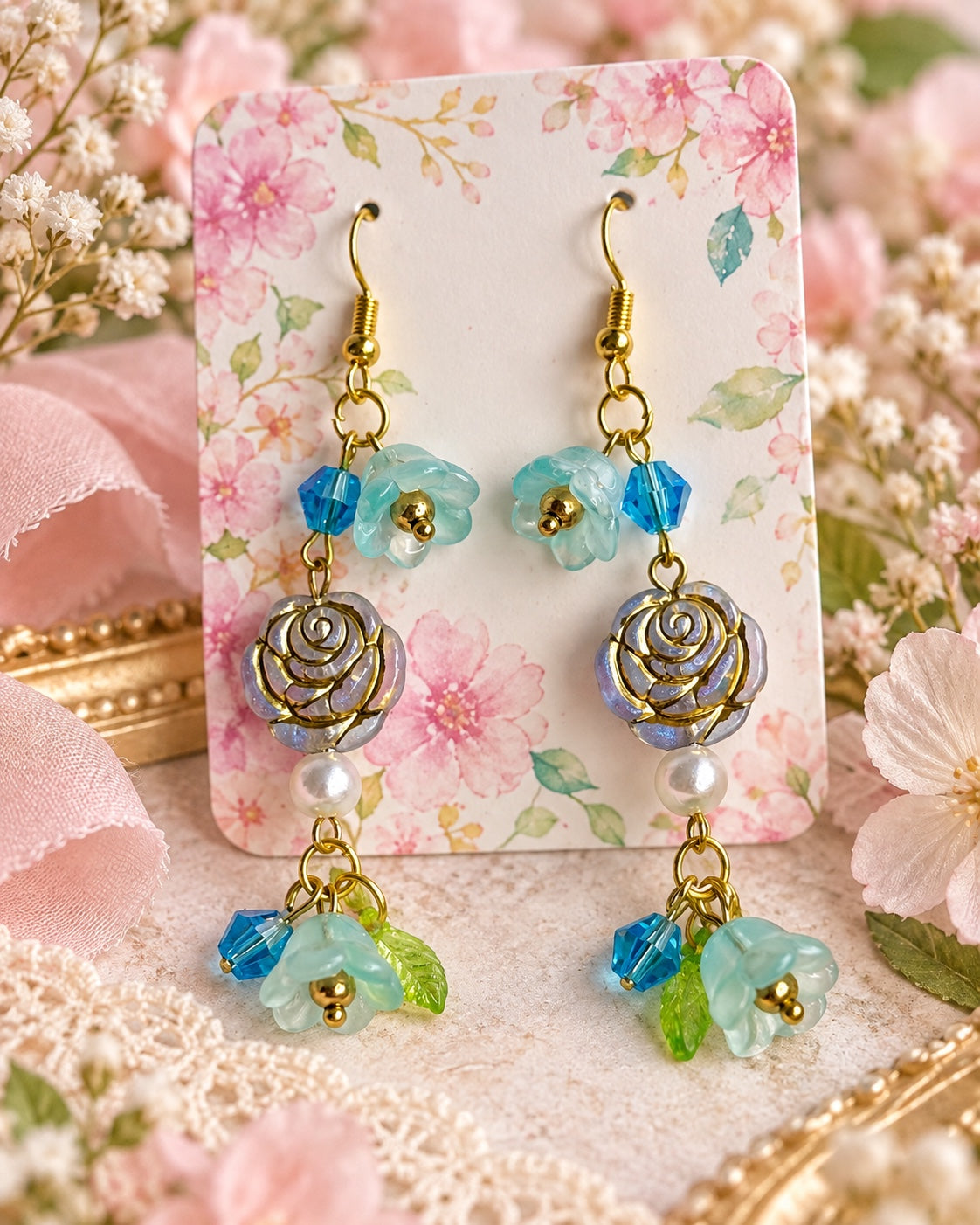 Aquarose Garden Earrings with aqua flowers, blue faceted beads, gold-outlined roses, pearl-style beads and green leaves