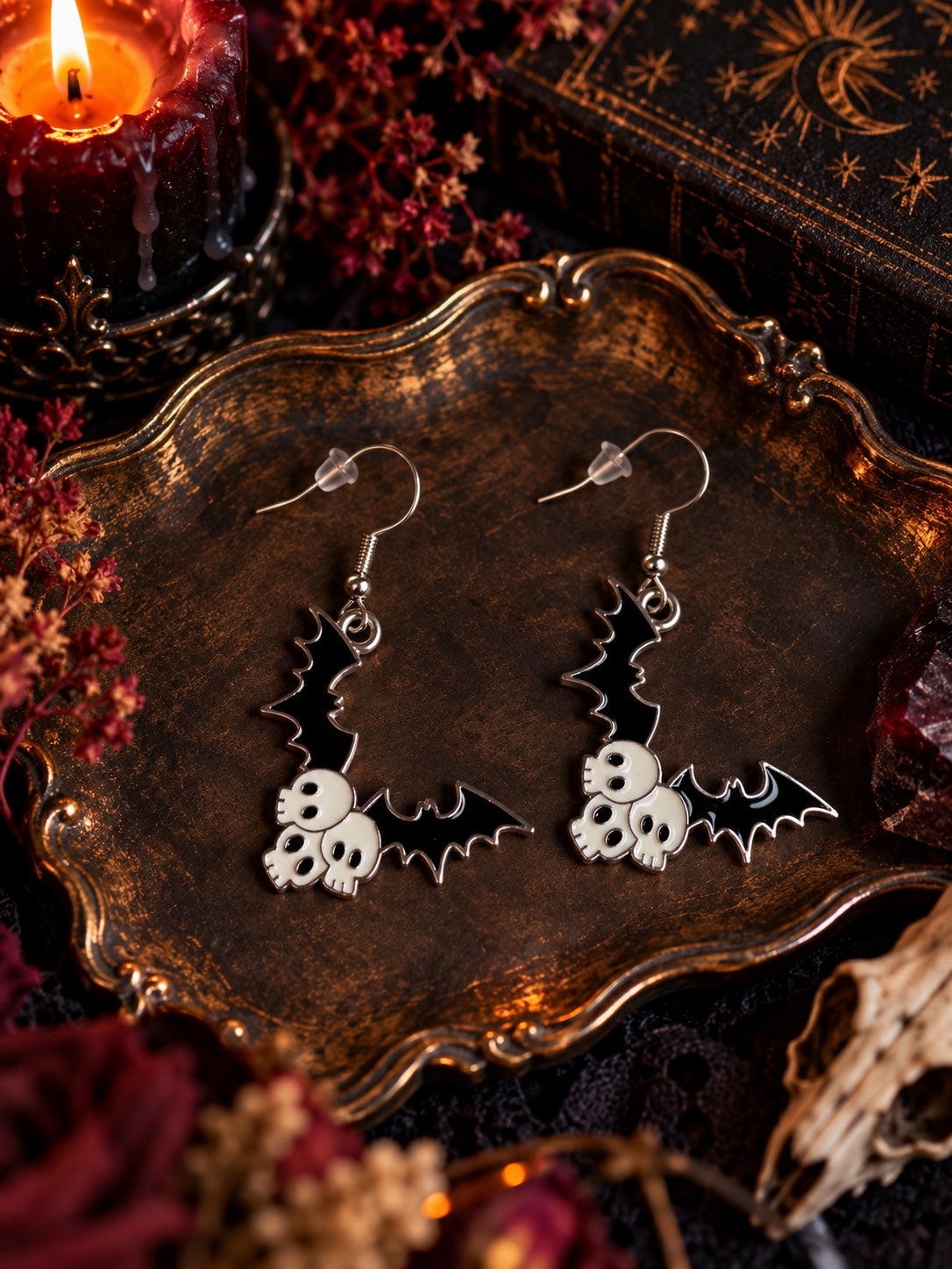 Black bat-wing earrings with three white skulls on each charm and silver-tone French hooks