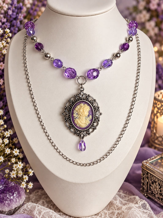 Purple beaded cameo necklace with ornate silver-tone frame, cream-coloured portrait, purple teardrop and long draped chain