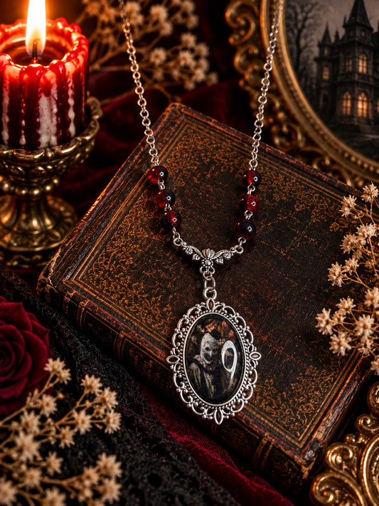 Horror portrait necklace with ornate silver-tone oval pendant, winged connector and dark red beads