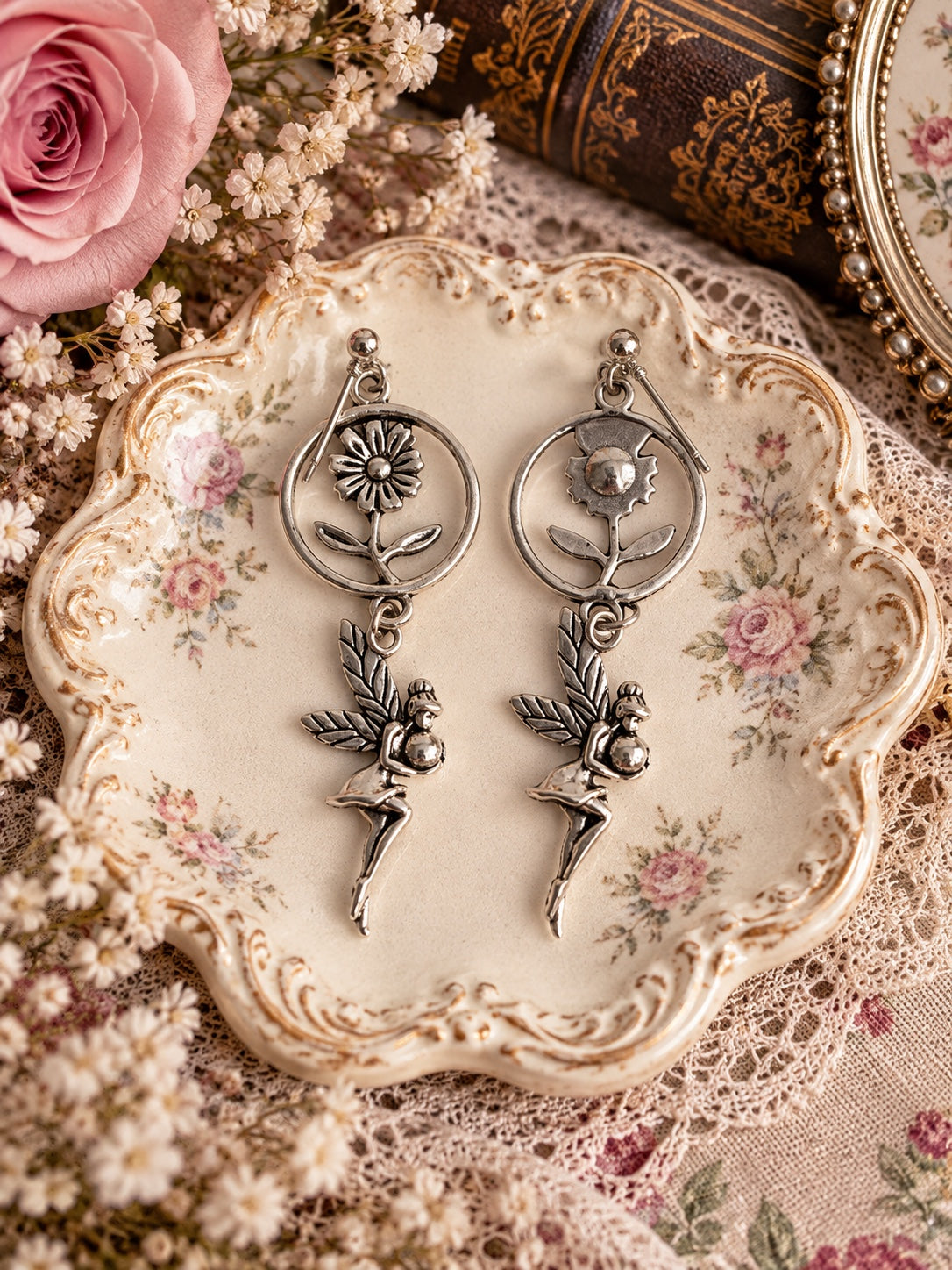 Silver-tone dangle earrings with flowers inside circular frames and winged fairy charms
