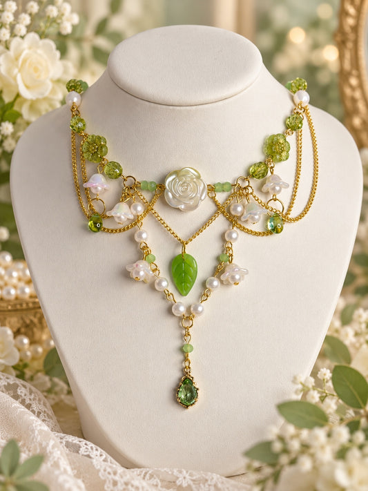Dewrose Garden Necklace with an ivory rose, green beads and leaf, white flowers, pearl-style strands and draped gold-tone chains
