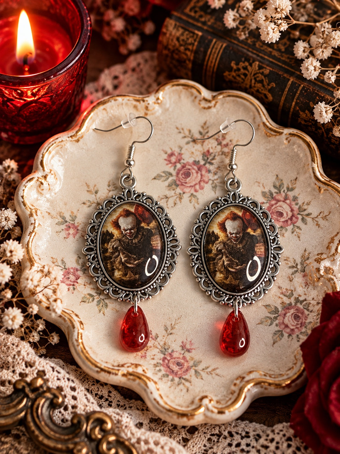 Silver-tone ornate cameo earrings featuring a sinister clown portrait and red teardrop beads