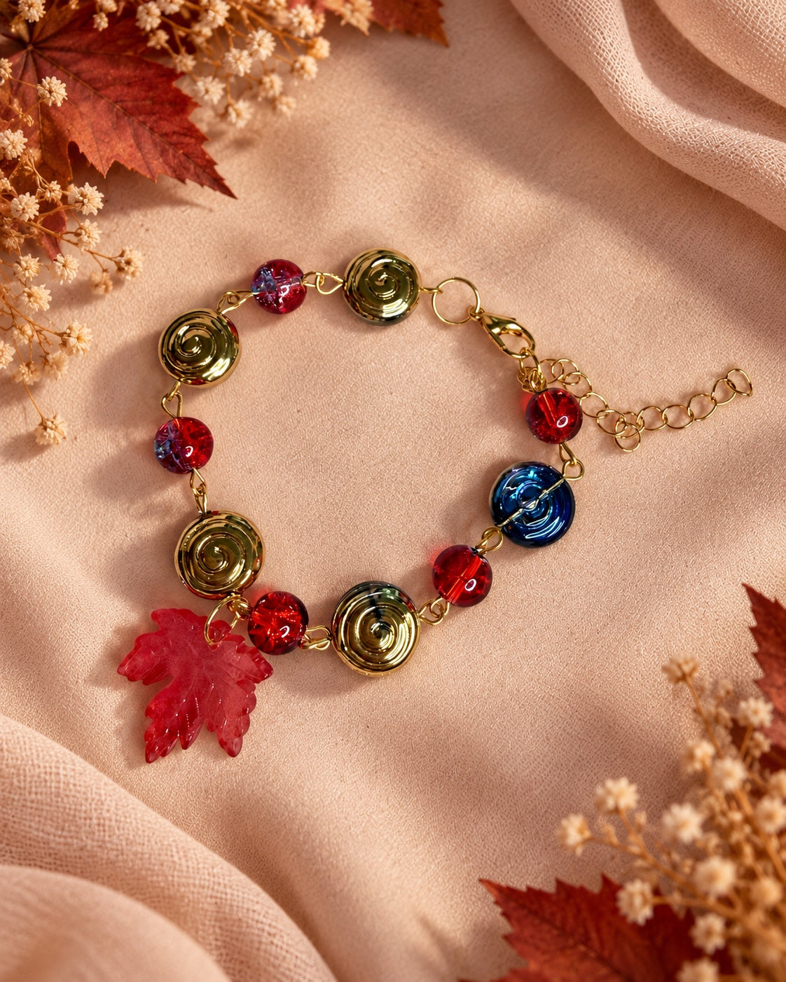 Dark fairycore bracelet with red beads, metallic spiral discs and a red maple leaf charm