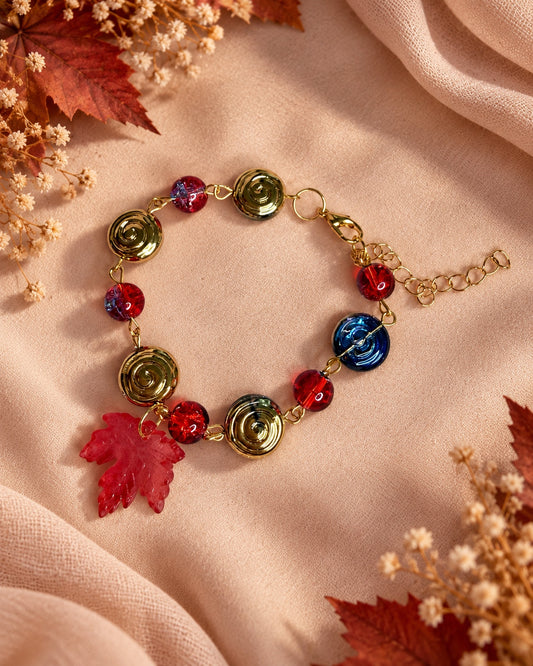 Dark fairycore bracelet with red beads, metallic spiral discs and a red maple leaf charm