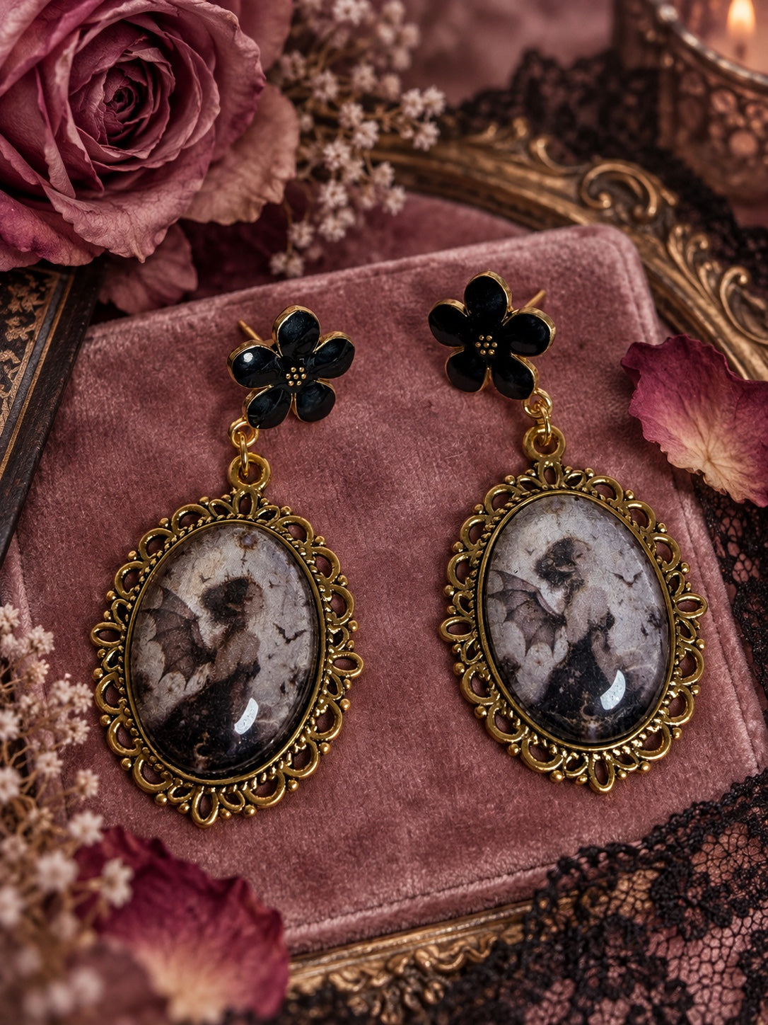 Nightpetal Muse Earrings with black flower studs and ornate gold-tone oval pendants featuring a dark winged fairy
