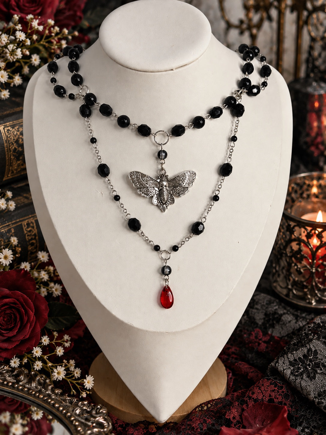 Layered Nightreign Moth Necklace with black beads, an ornate silver-tone skull moth pendant and a red teardrop