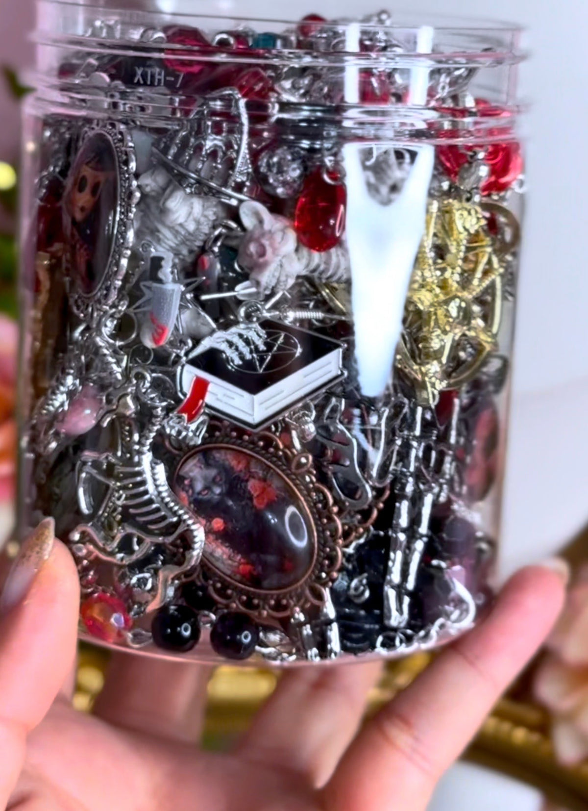 Close view of a Patricia Braham inspired horror mystery jewelry jar with gothic charms, chains and cameo-style pieces