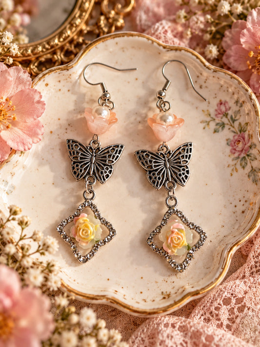 Silver-tone butterfly earrings with peach flowers, faux pearl centres and sparkling diamond-shaped frames with pastel roses