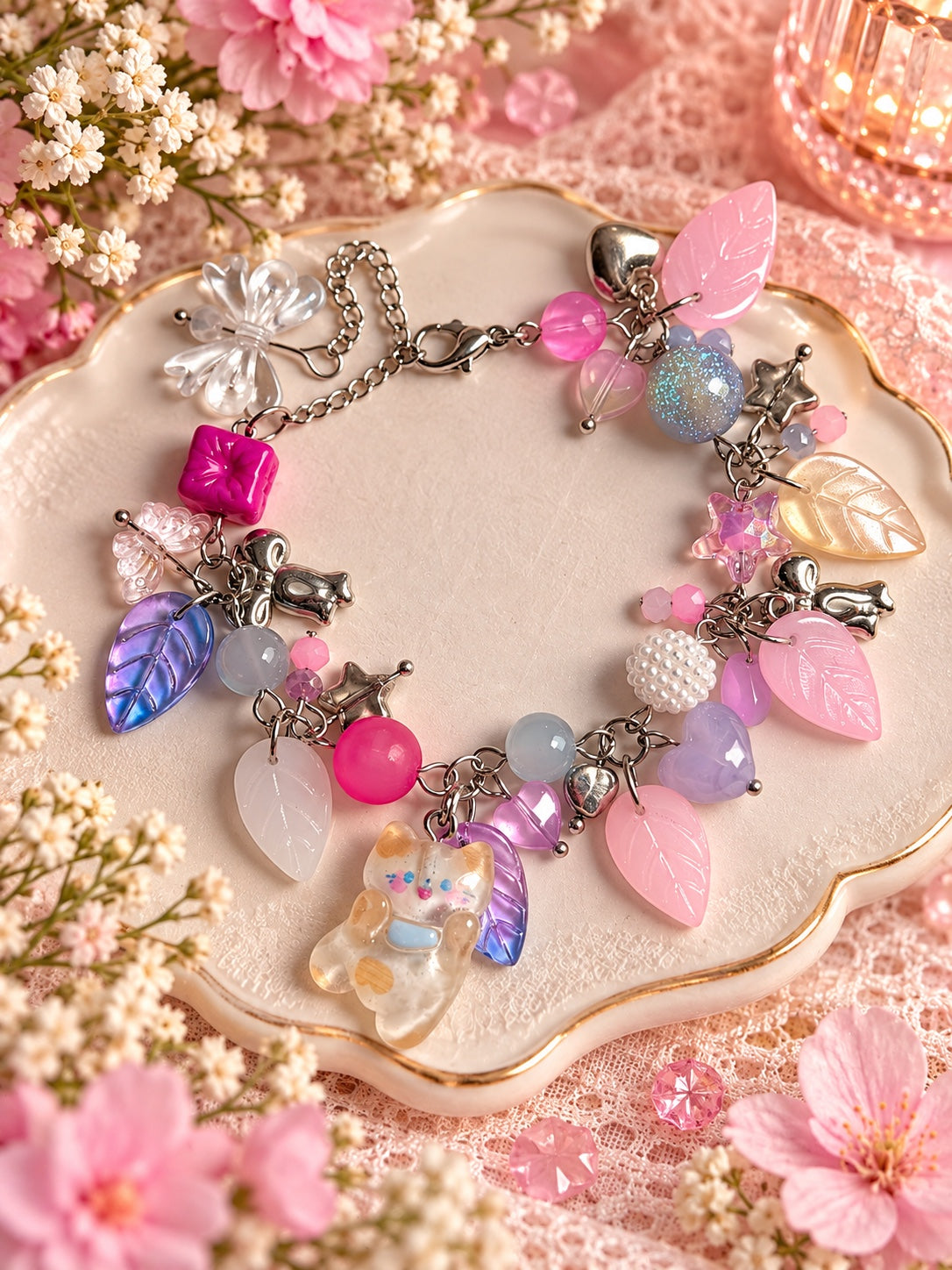 Pastel charm bracelet with a waving cat, pink and iridescent leaves, hearts, stars and bows