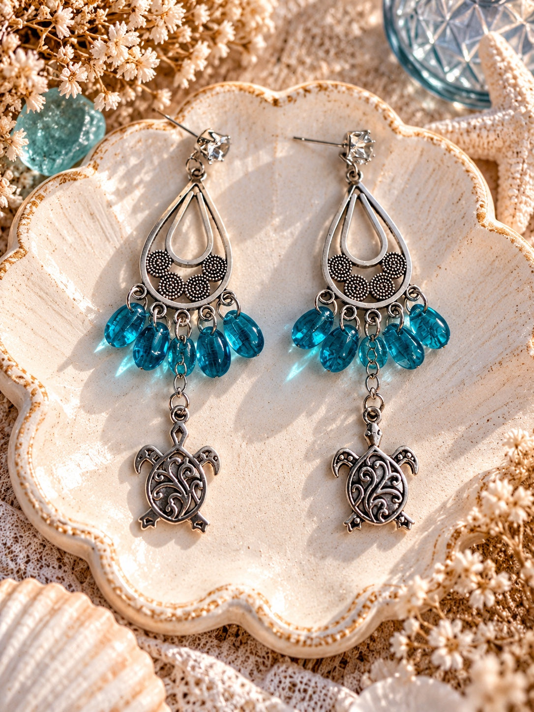 Silver-tone chandelier earrings with turquoise-blue teardrop beads, filigree sea turtle charms and clear rhinestone studs