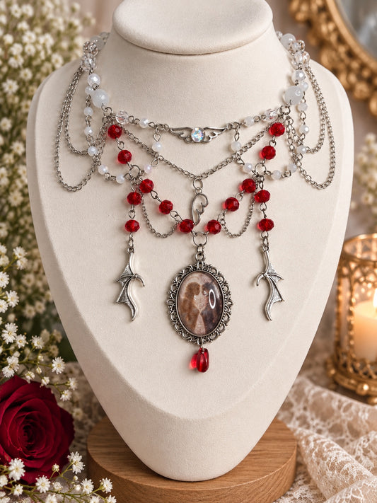 Layered silver-tone angelcore and gothic necklace with red and white beads, wing charms and an oval cameo