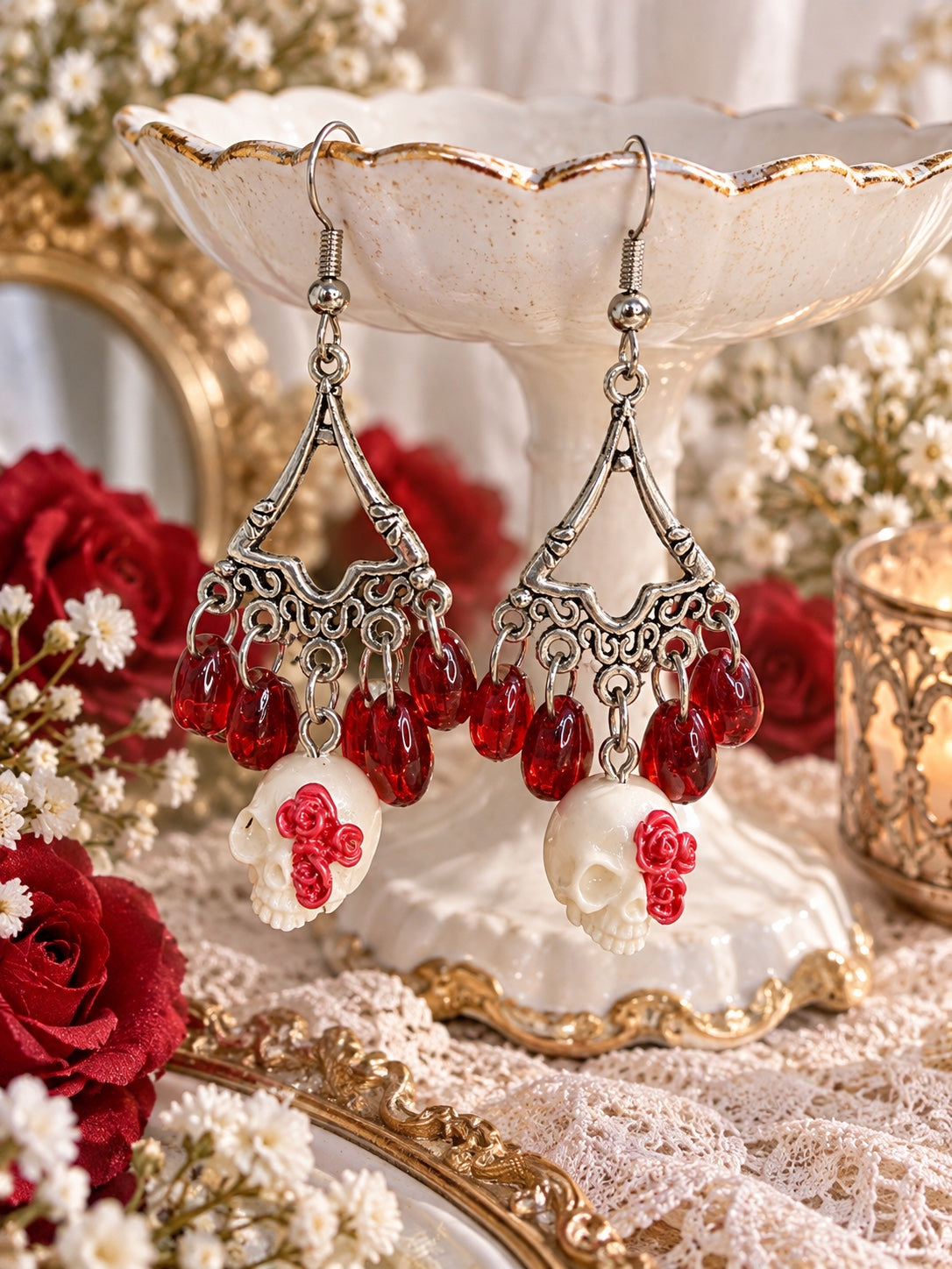 Silver-tone chandelier earrings with red teardrop beads and ivory skull charms decorated with red roses