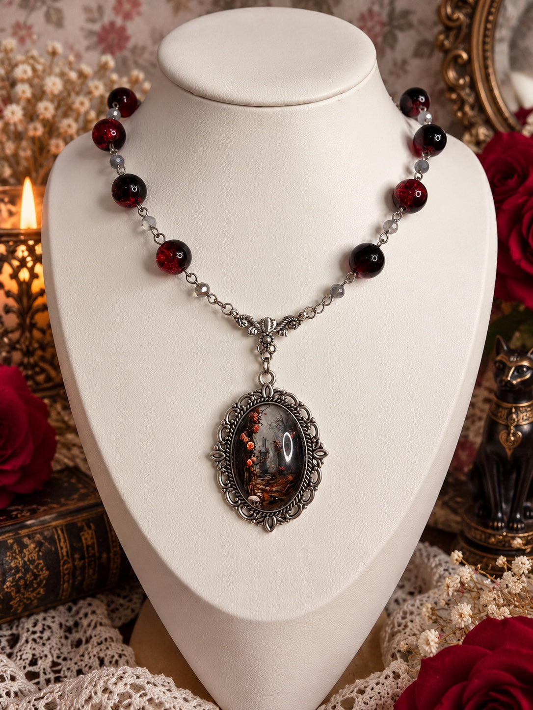 Silver-tone necklace with dark red crackle beads, grey beads and an ornate oval cameo showing a shadowy gothic garden
