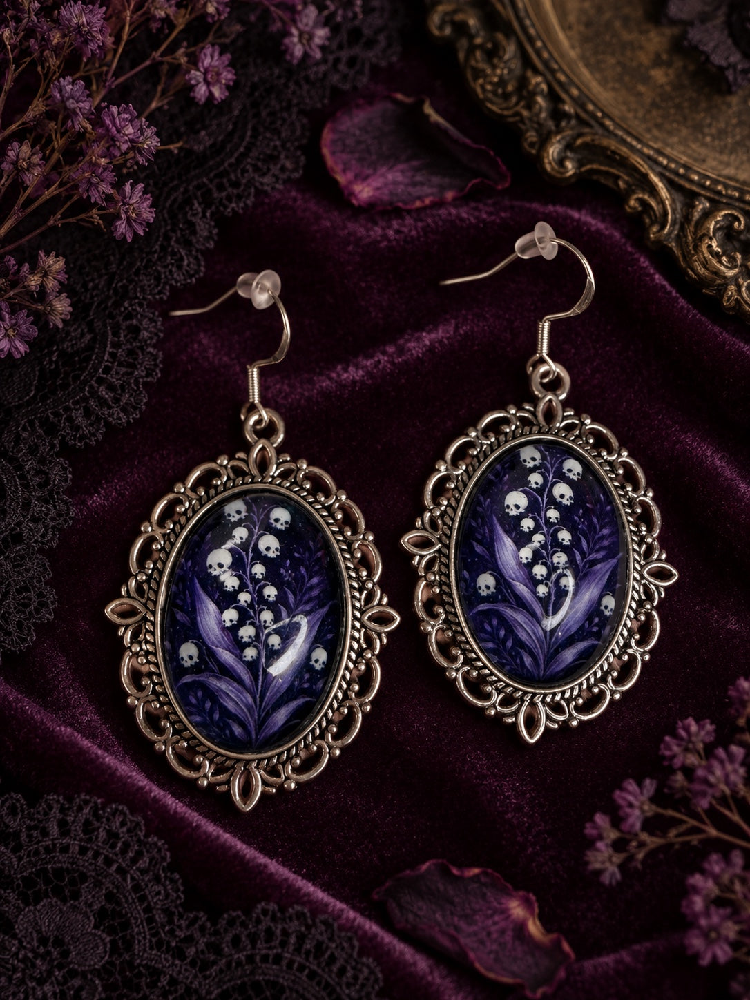 Ornate silver-tone oval earrings with purple foliage and white skull-shaped flowers, on 925 sterling silver hooks.
