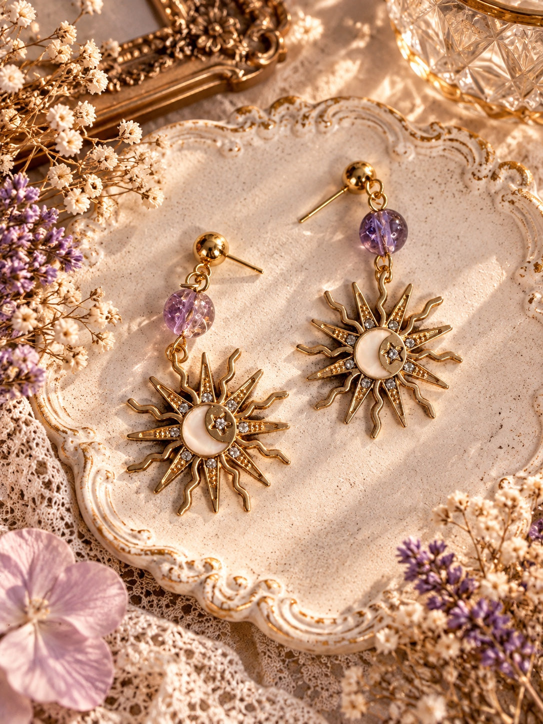 Gold-tone sunburst earrings with crescent moon and star details, clear rhinestones and lavender beads