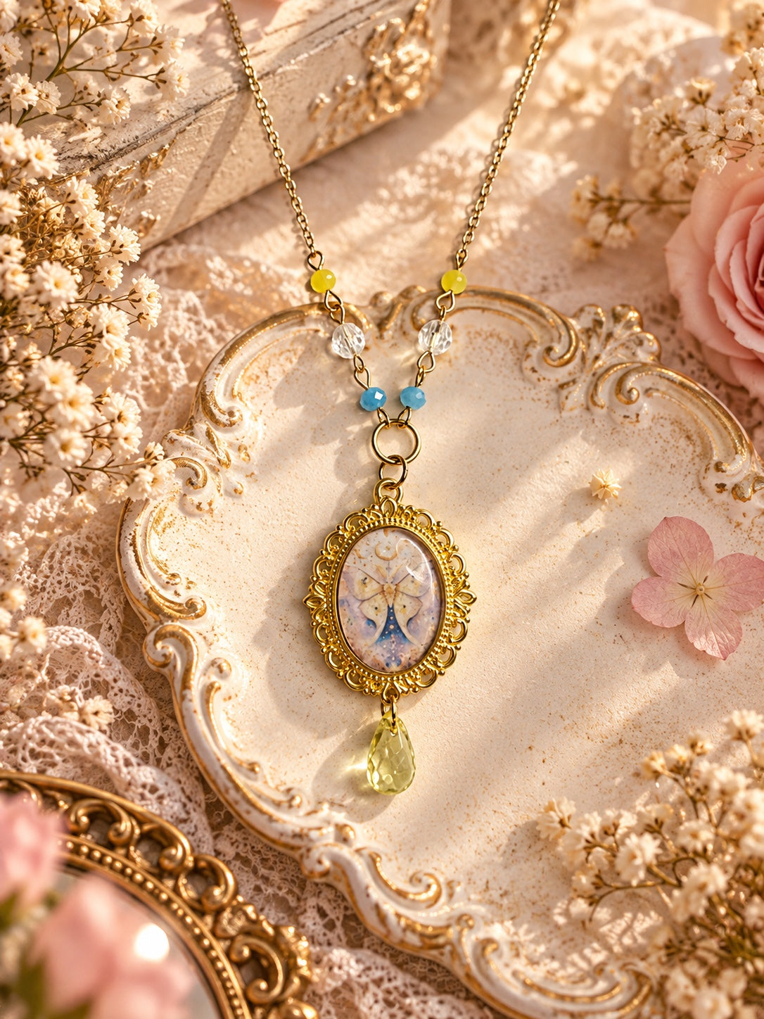 Gold-tone necklace with celestial moth cameo, yellow and blue beads, clear accents and yellow teardrop pendant