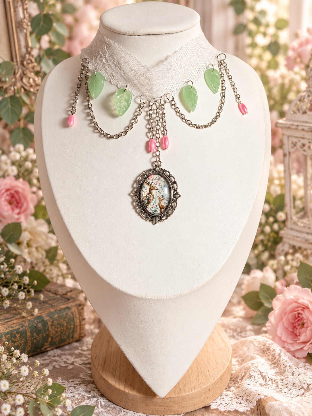 Ivory lace choker with pale green leaf charms, pink bead drops, draped silver-tone chains and an ornate oval pendant illustrating two deer.