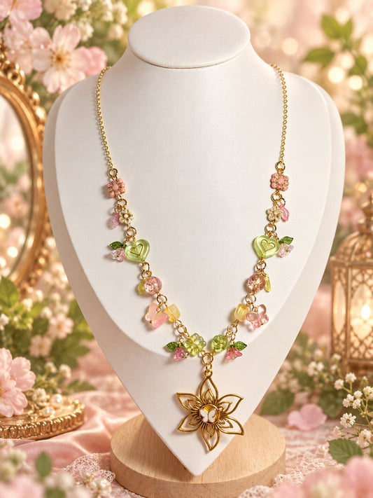 Gold-tone floral necklace with pink and green charms, green hearts and an openwork flower pendant with a butterfly centre.