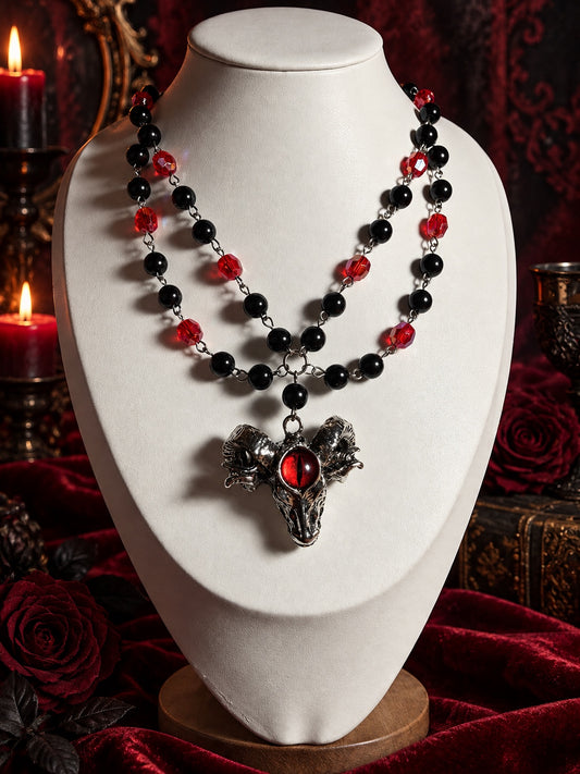 Double-strand black and red beaded necklace with a silver-tone horned skull pendant and a red slit-pupil eye at its centre.