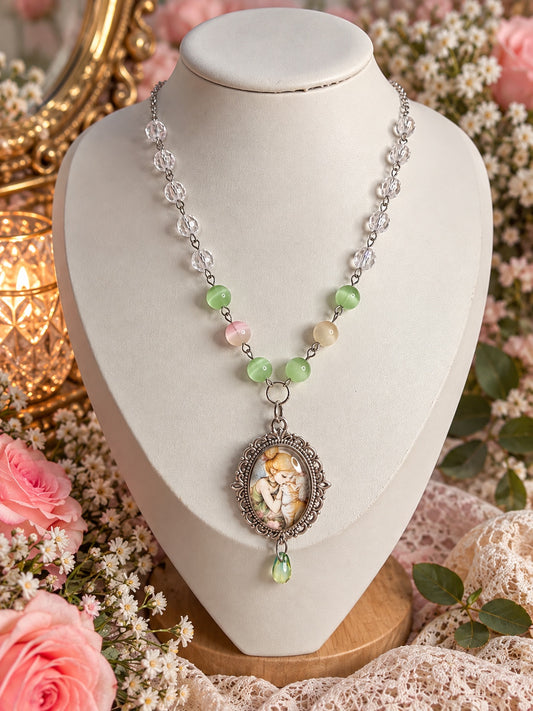 Silver-tone necklace with clear and pastel green beads, an oval fairy and cat cameo and a green teardrop.