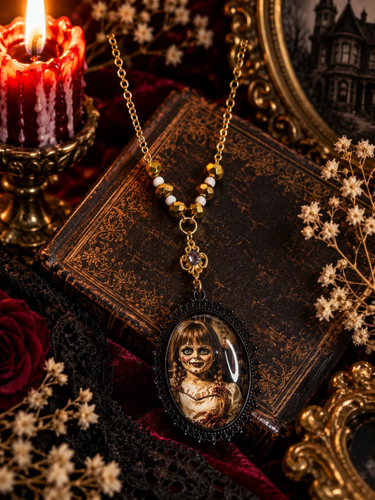 Gold-tone necklace with gold and white beads, an ornate connector and a black oval Annabelle portrait pendant.