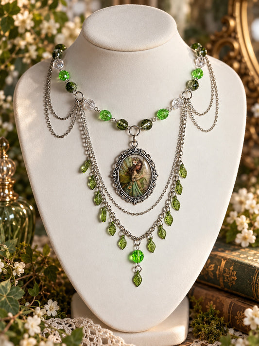 Green fairy cameo necklace with clear and green beads, layered silver-tone chains and dangling green leaf charms.