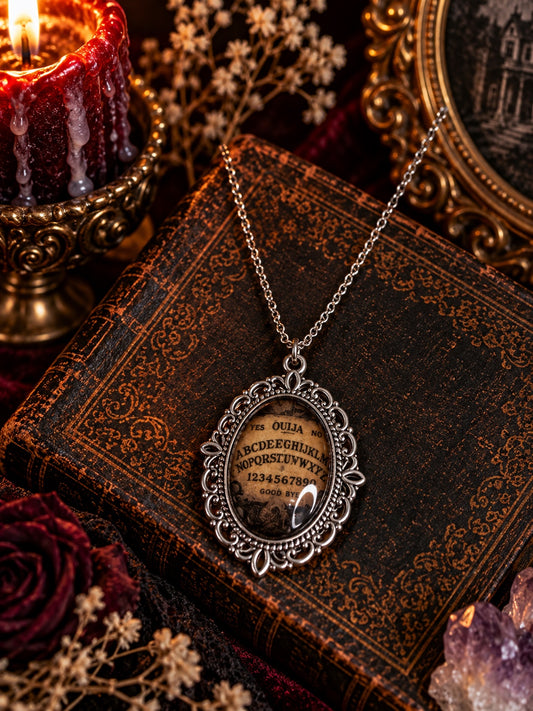 Silver-tone oval pendant necklace with an antique-style Ouija board motif and ornate frame.