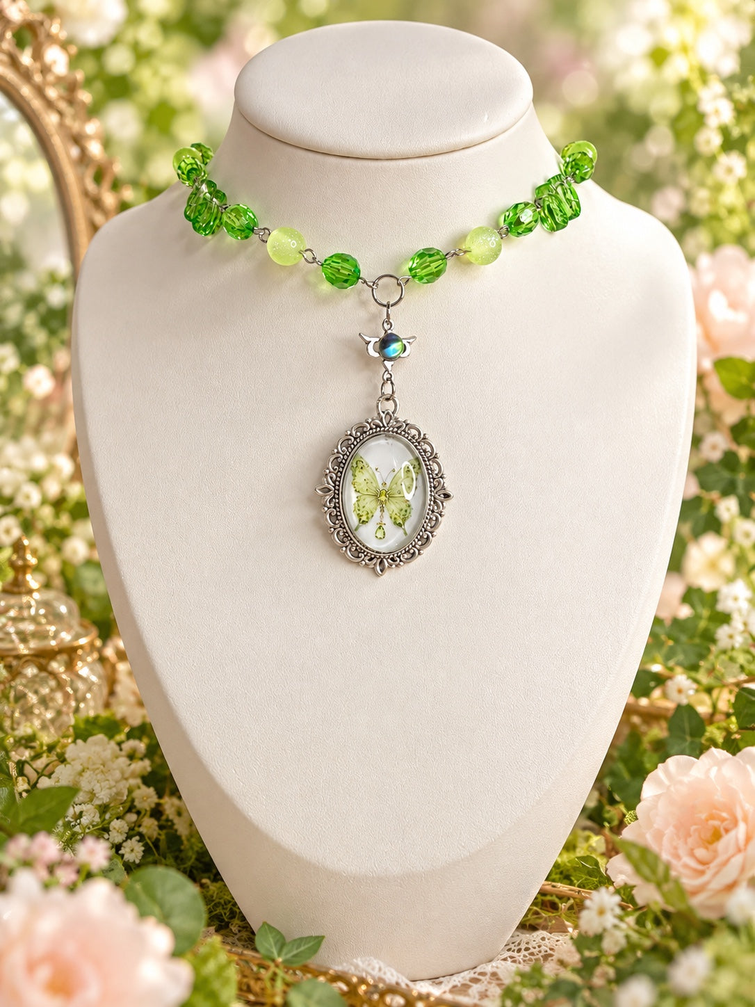 Green beaded silver-tone necklace with an ornate oval green butterfly cameo and a small iridescent winged detail.