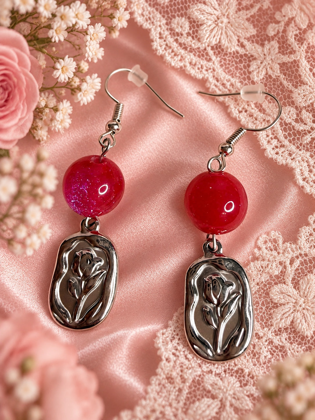 Silver-tone rose relief drop earrings with shimmering raspberry-pink round beads and fishhook ear wires.