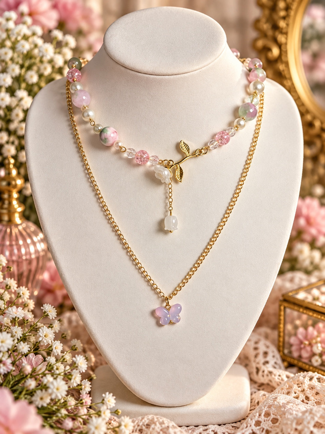 Layered gold-tone necklace with pastel pink and green beads, pearly accents, a white rose on a leafy stem and a lavender butterfly pendant.