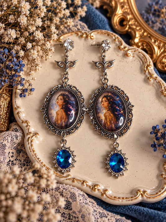 Long silver-tone earrings with celestial portrait cameos, clear stud tops and vivid blue oval decorative drops.