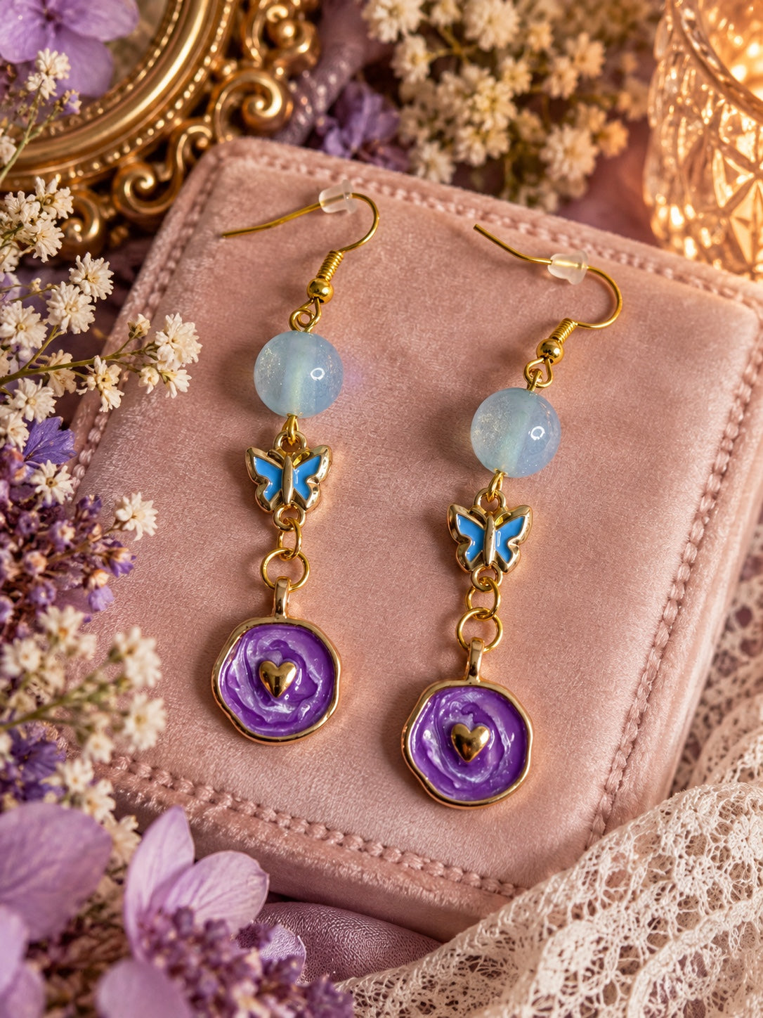 Gold-tone drop earrings with pale blue beads, blue butterflies and purple rose-shaped discs with gold-tone hearts.