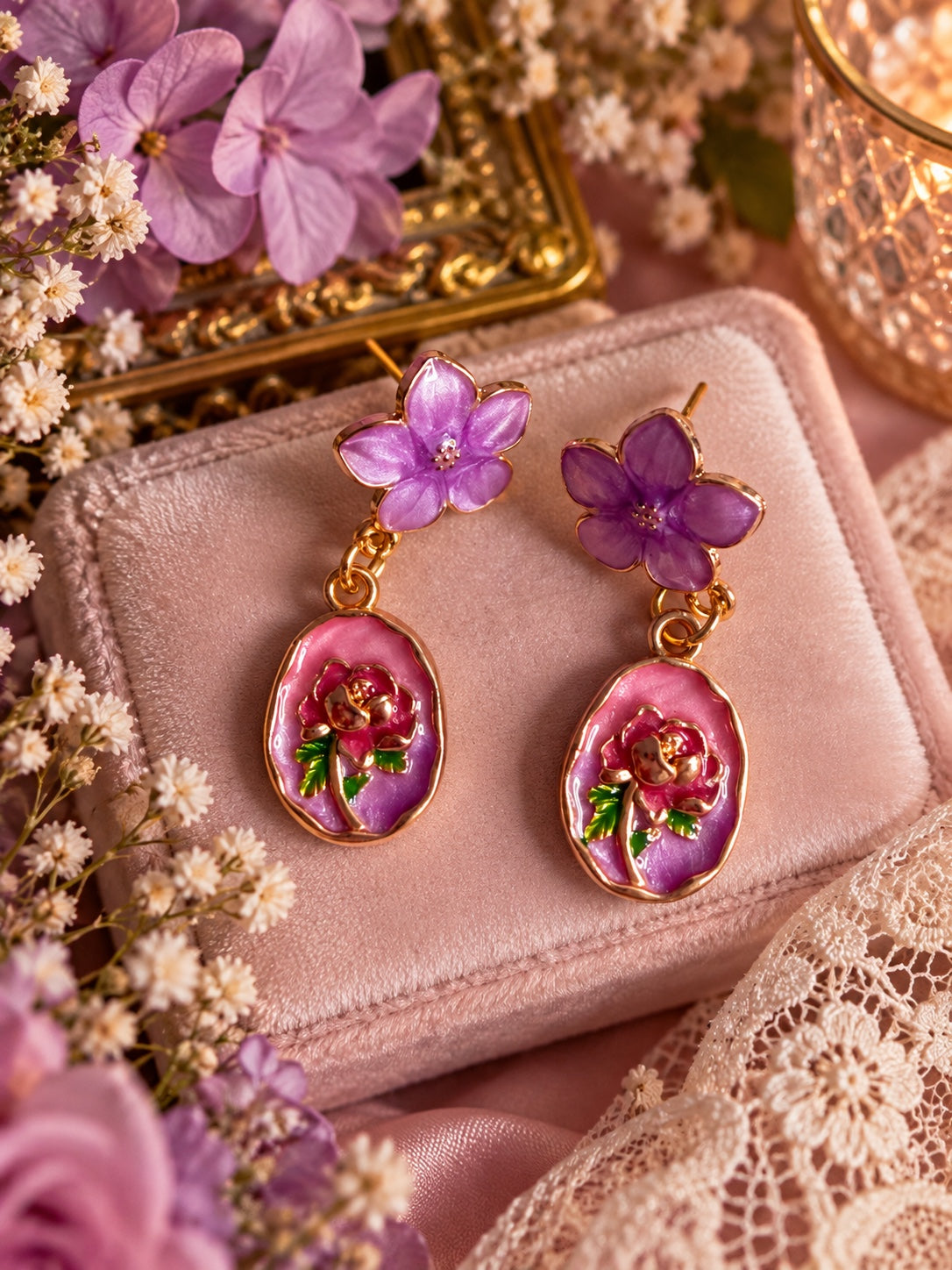 Gold-tone drop earrings with purple flower studs and pink-purple oval pendants decorated with roses and green leaves.