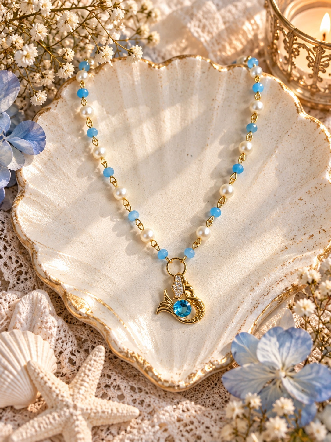 Gold-tone mermaid pendant necklace with blue beads, white faux pearls and a blue sparkling accent