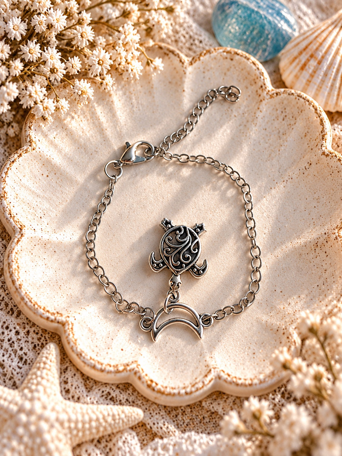 Silver-tone adjustable chain bracelet with an open crescent moon connector and ornate sea turtle charm