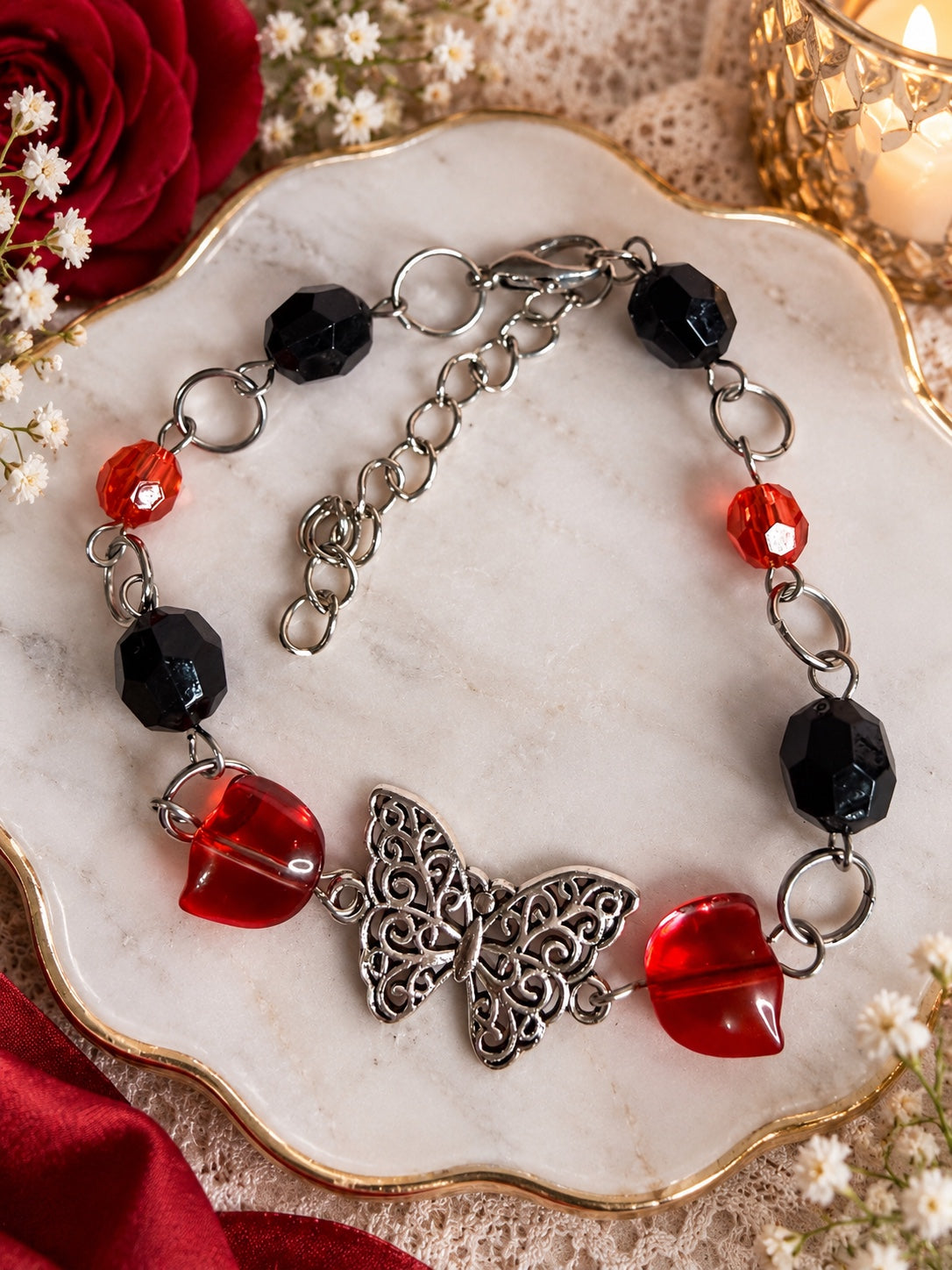 Silver-tone filigree butterfly bracelet with red hearts and black and red faceted beads