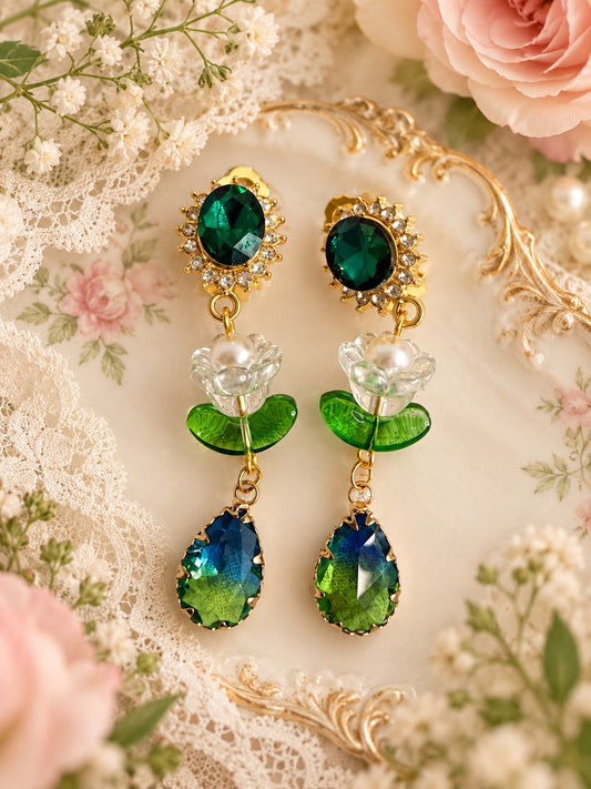 Gold-tone drop earrings with dark green oval studs, clear flowers with faux pearl centres, green leaves and blue-green teardrops