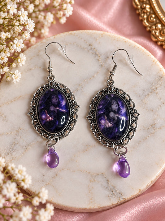 Ornate silver-tone sorceress portrait earrings with purple teardrop beads